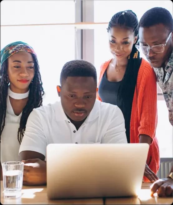 four people looking at a laptop screen